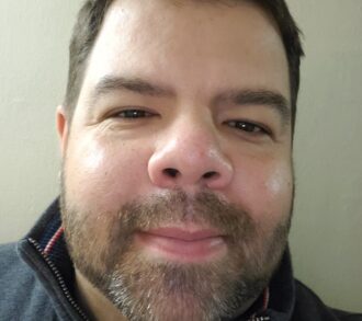 a man wearing glasses and smiling at the camera